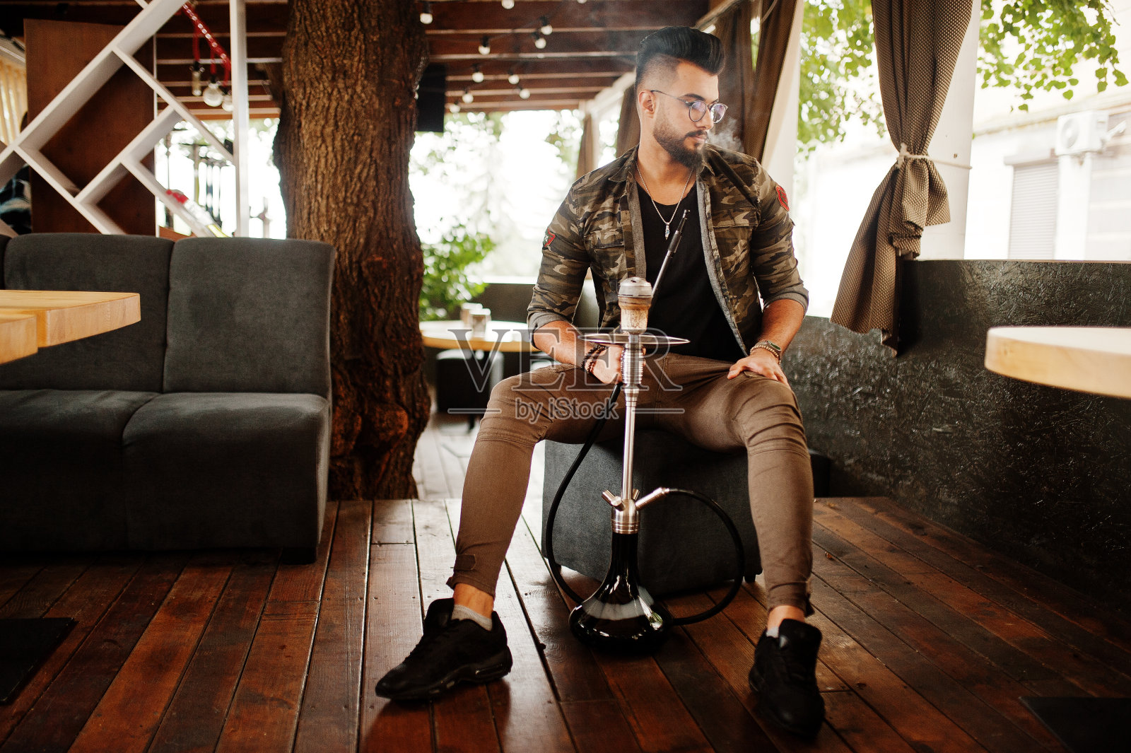 留着时尚胡须的阿拉伯男人抽水烟照片摄影图片