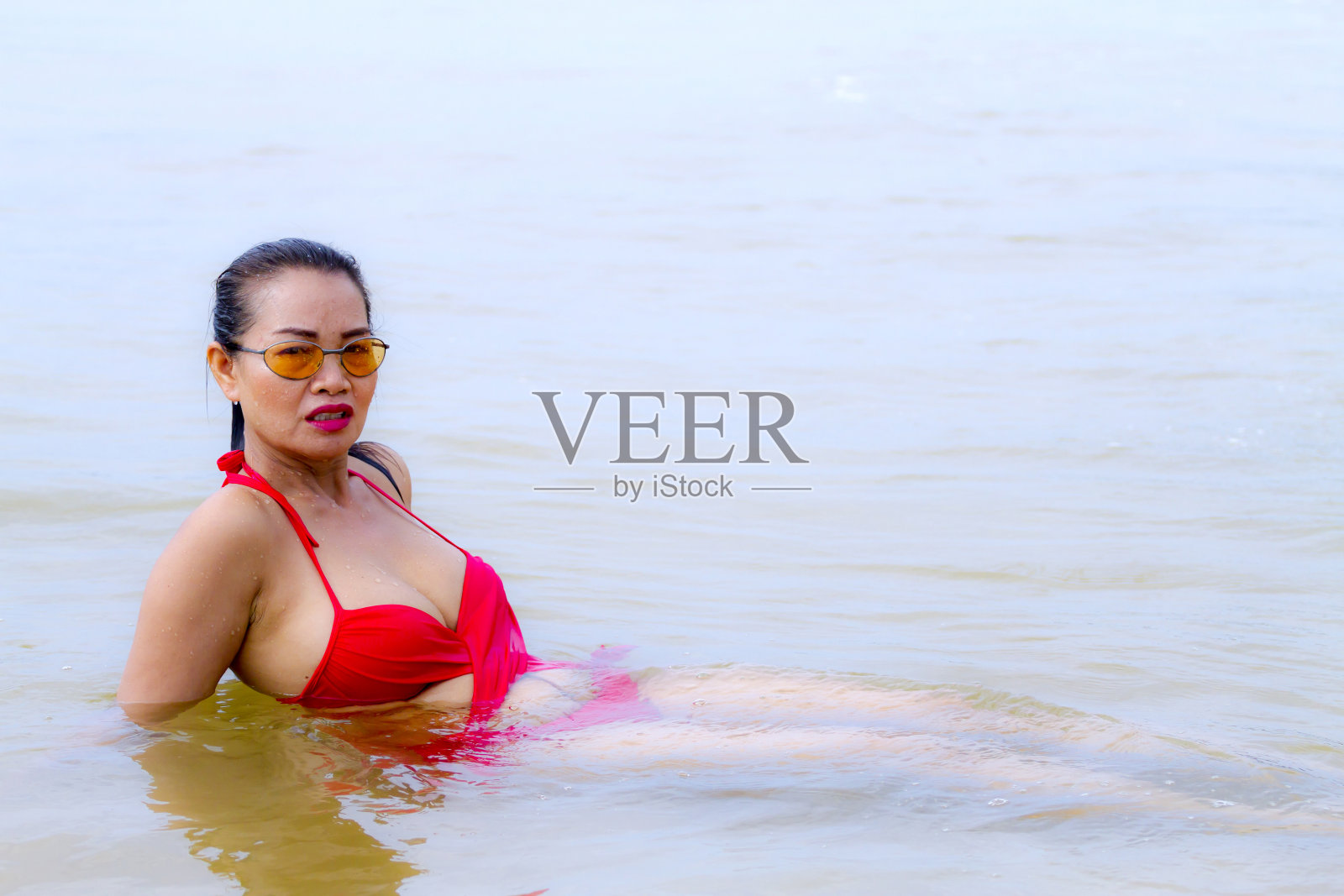 在Bang Boet海滩上，穿着红色比基尼的女人在水里照片摄影图片