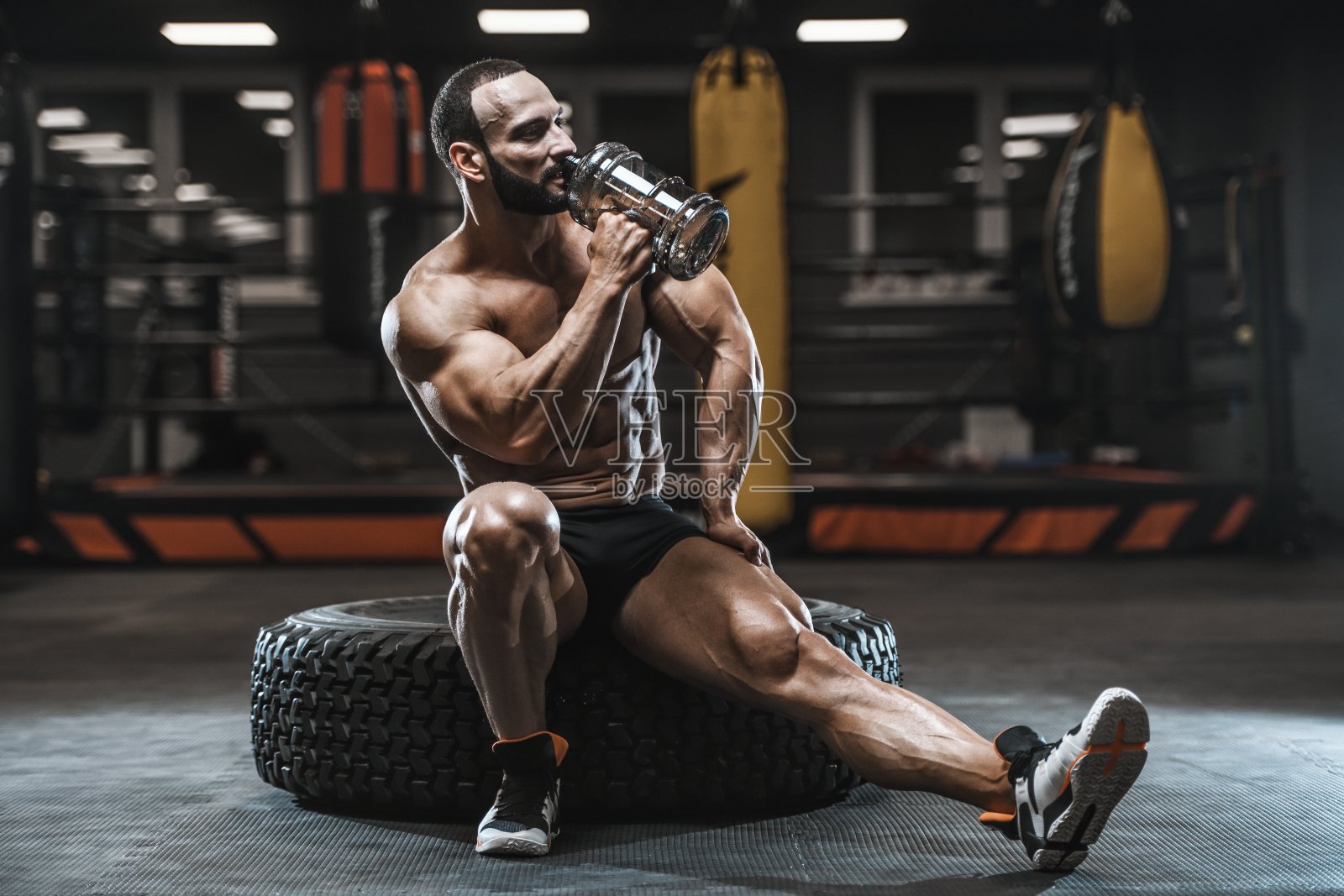 野蛮强壮的健美运动员用哑铃锻炼肌肉照片摄影图片