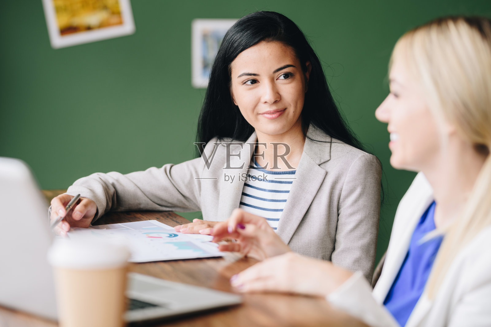 内容有吸引力的年轻混血女经理听同事在咖啡馆讨论财务和预算和分析文件照片摄影图片