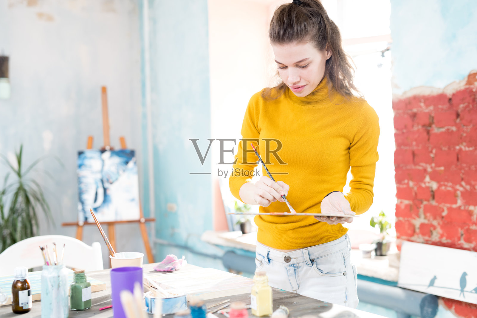 内容启发漂亮的女孩在黄色高领混合调色板上的颜色，而准备在艺术工作室绘画照片摄影图片