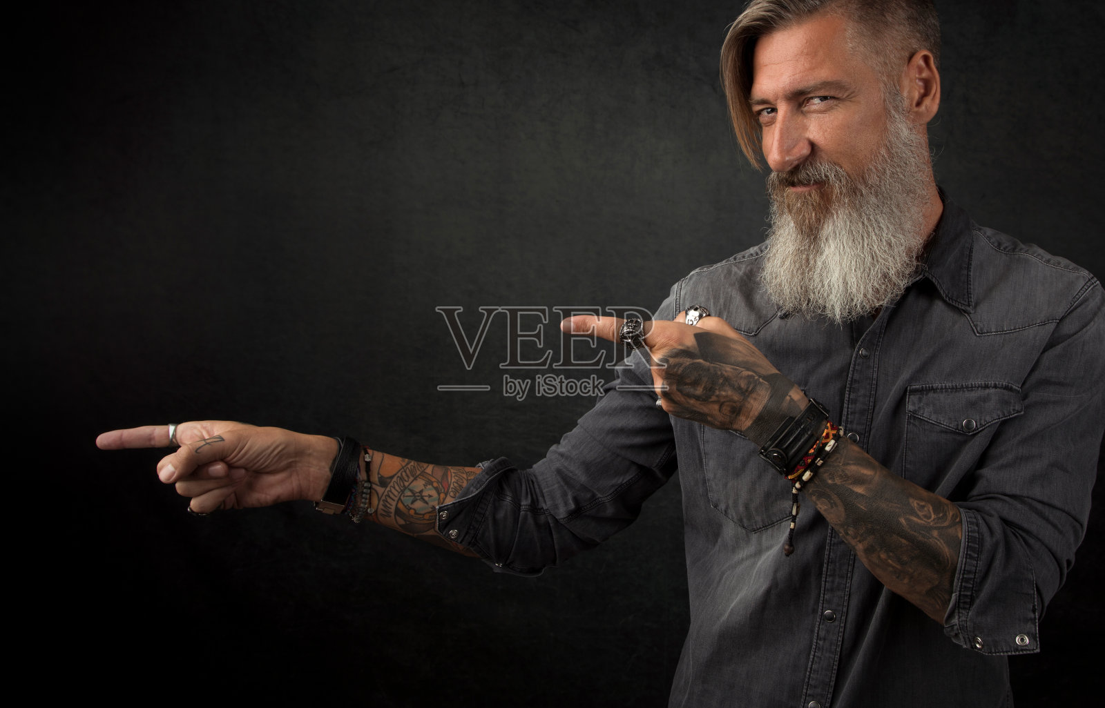 一个留着胡子的嬉皮士的肖像，他的手指指着什么，孤立在一个黑色的背景照片摄影图片