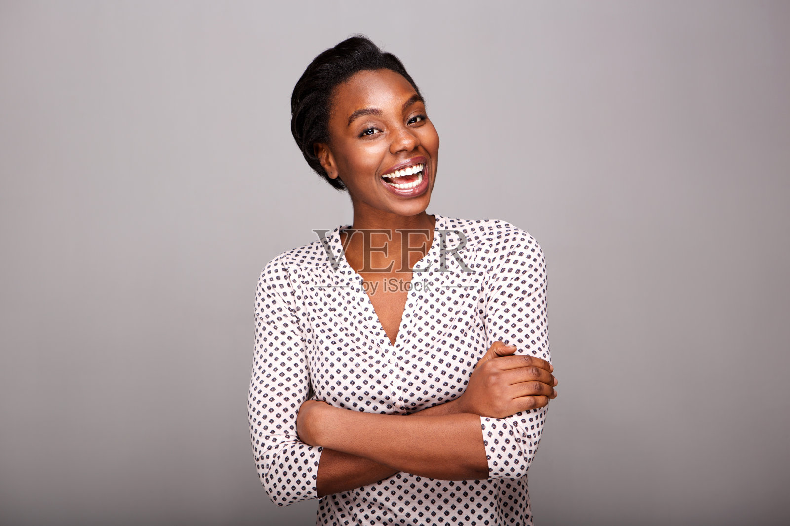 时尚的女人笑着，双臂交叉站在那里照片摄影图片