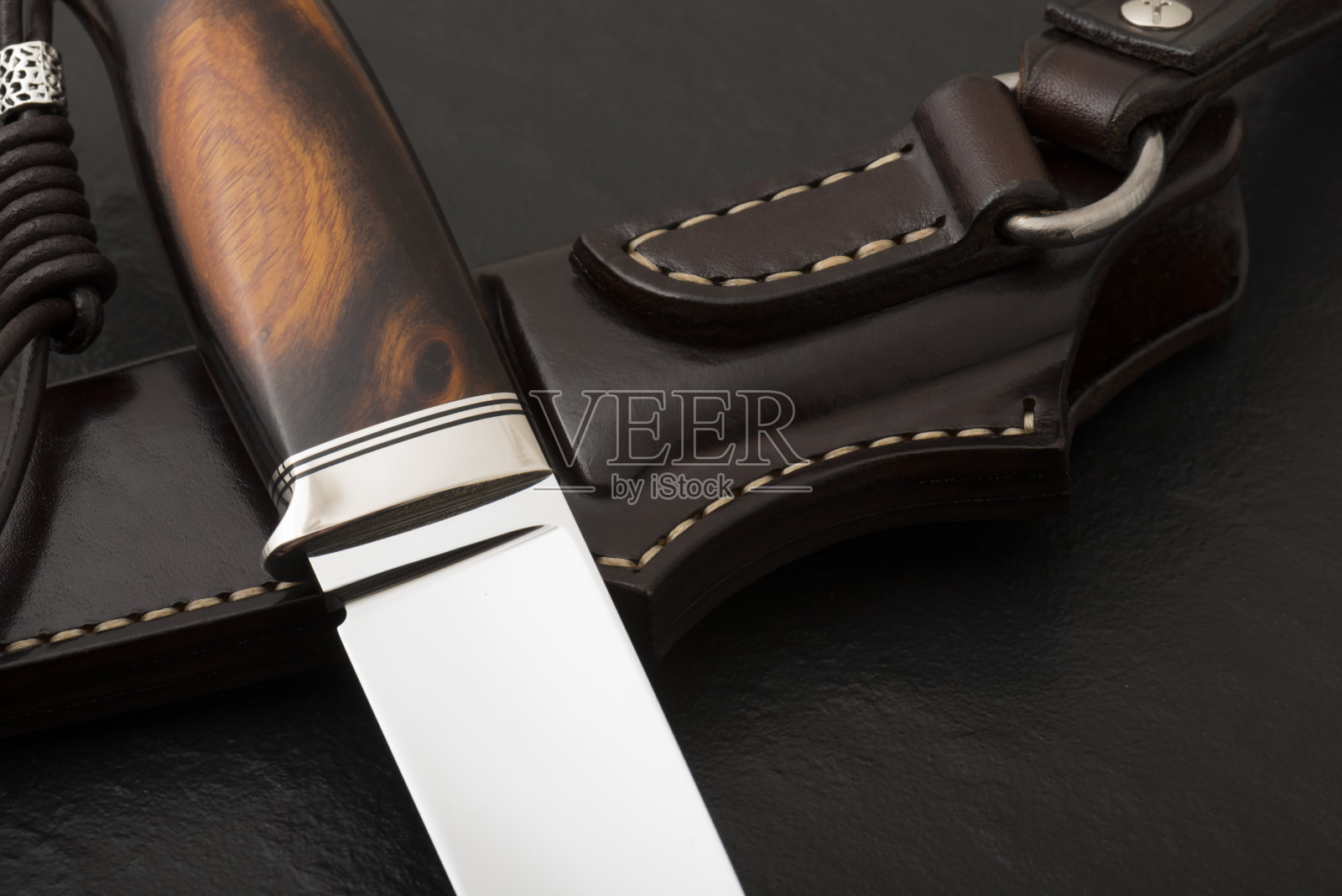 在黑色背景上手工制作的猎刀。皮鞘手工制作的照片摄影图片