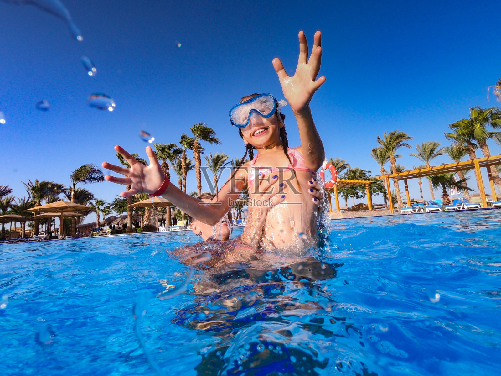 快乐的母女在埃及度假游泳池里玩耍照片摄影图片