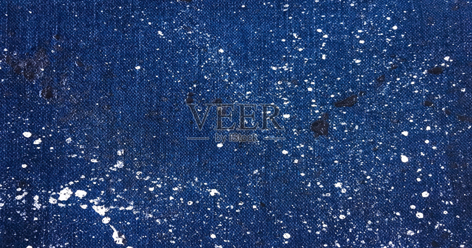 牛仔布，牛仔裤纹理背景。在蓝色背景的牛仔布上滴上几滴彩色颜料。照片摄影图片