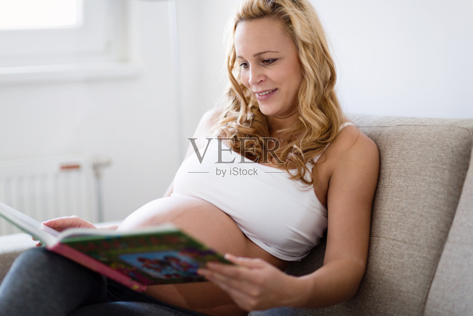 孕妇在沙发上休息和阅读书籍照片摄影图片