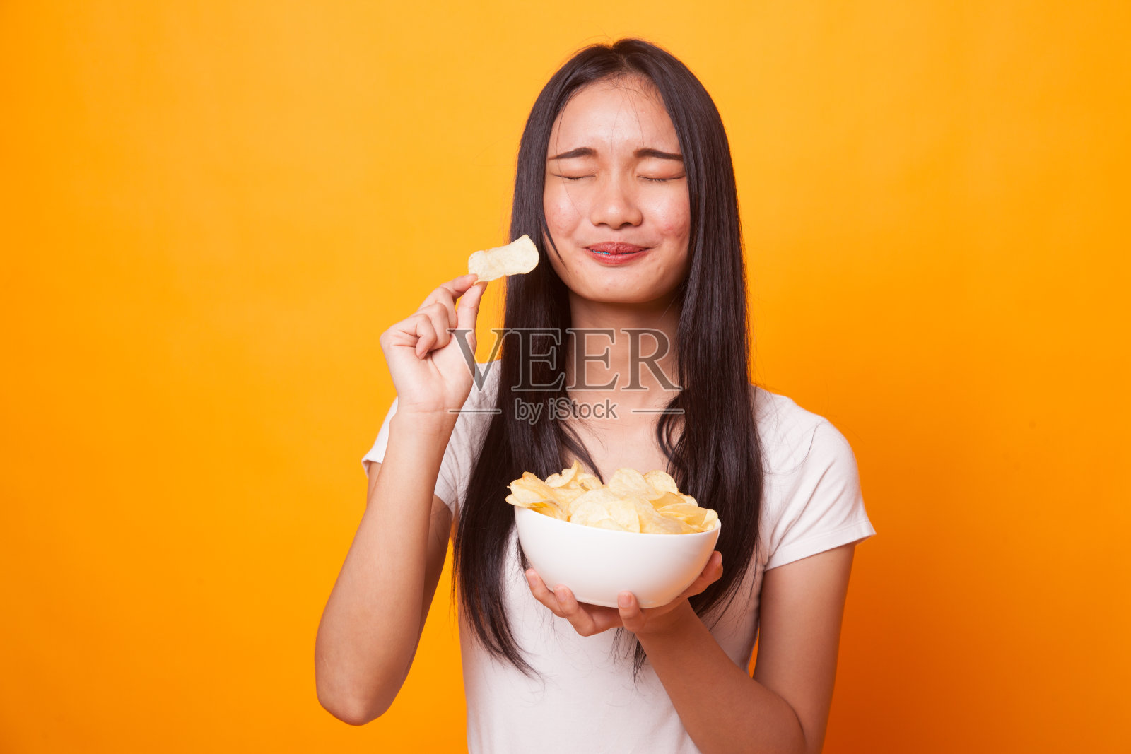 年轻的亚洲妇女吃薯片。照片摄影图片