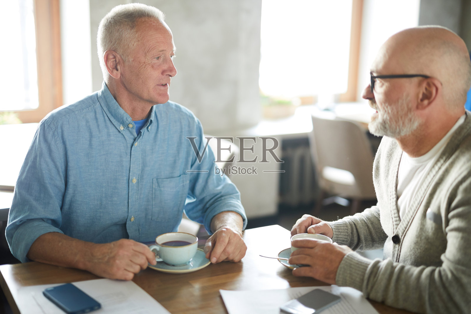 内容自信成熟的男性朋友在休闲服装坐在桌子和喝咖啡，而讨论最新的新闻在现代咖啡馆照片摄影图片