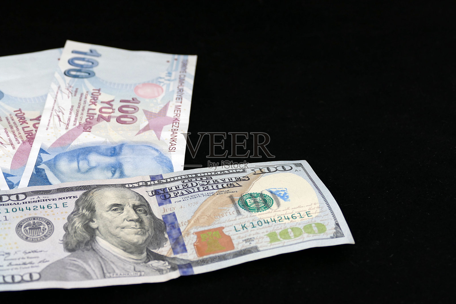 100土耳其里拉和100美元放在黑色地板上，照片摄影图片