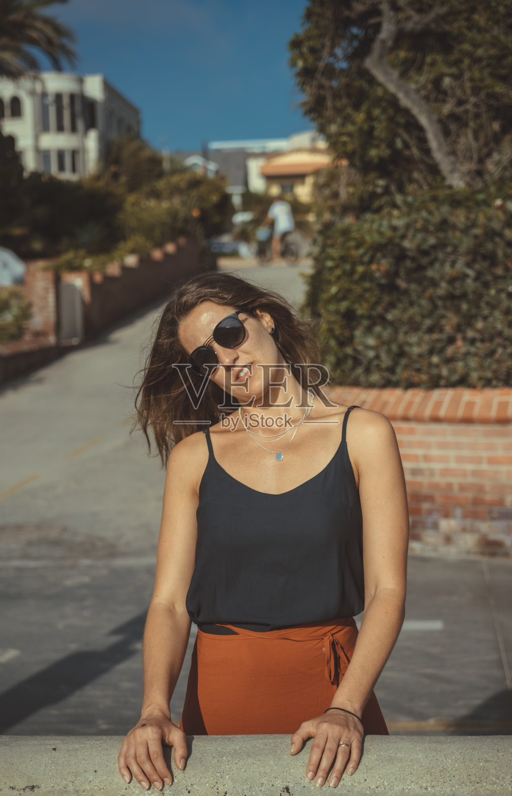 在傍晚的阳光下，一个非常成功的金发美女靠在墙上照片摄影图片