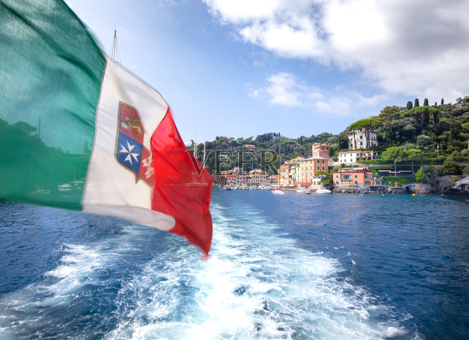 意大利国旗迎风飘扬，背景是古色古香的波托菲诺湾。照片摄影图片