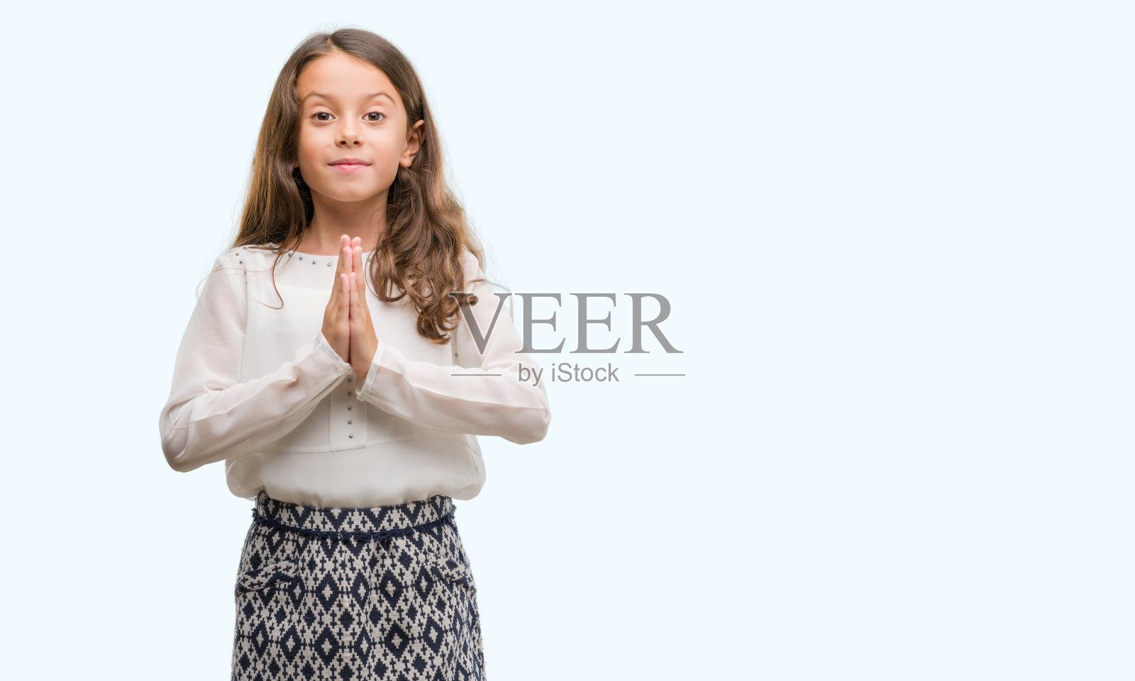 深色头发的西班牙女孩双手一起祈祷，自信地微笑着请求原谅。照片摄影图片