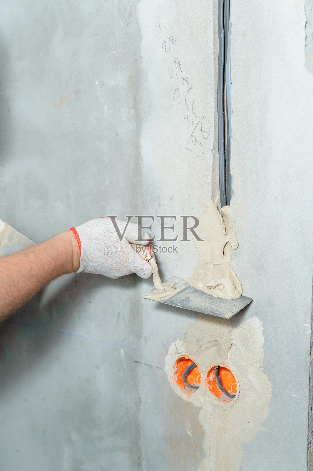 一个工人正在往墙上抹电波纹管。照片摄影图片