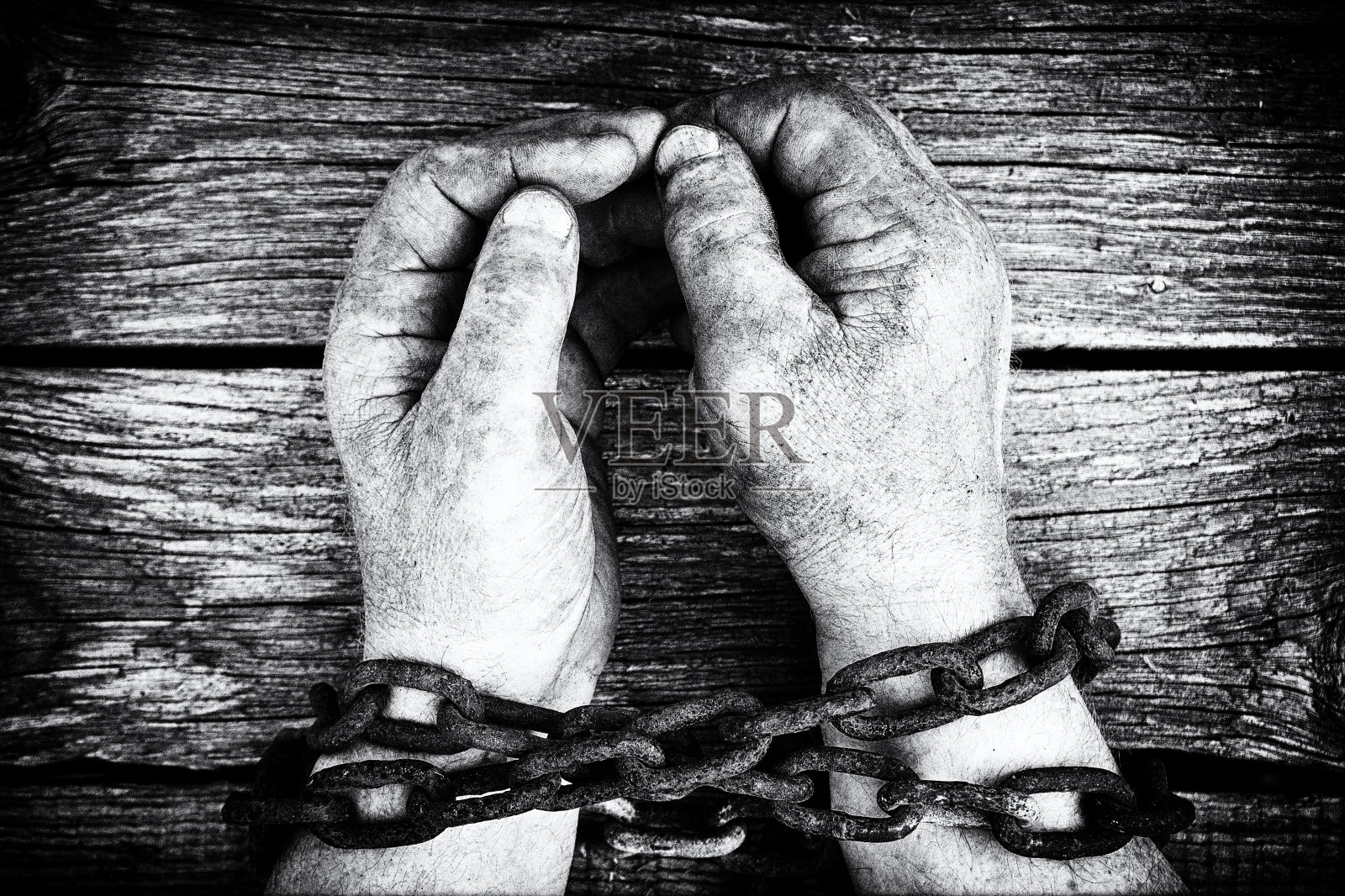 肮脏的男性双手被生锈的粗铁链锁在木板上照片摄影图片