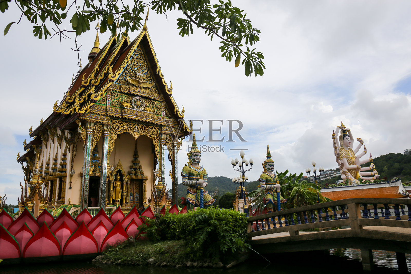 位于泰国苏梅岛普兰寺(Wat Plai Laem)的泰国寺庙，在水的中央，有巨大的雕像和大象。鸽子飞过。照片摄影图片