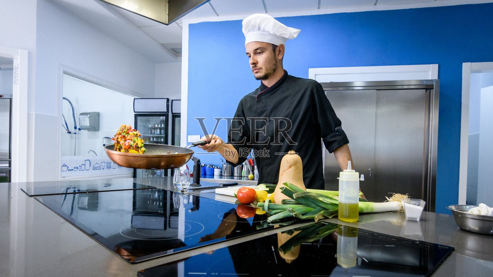 年轻的厨师在平底锅里搅拌蔬菜照片摄影图片