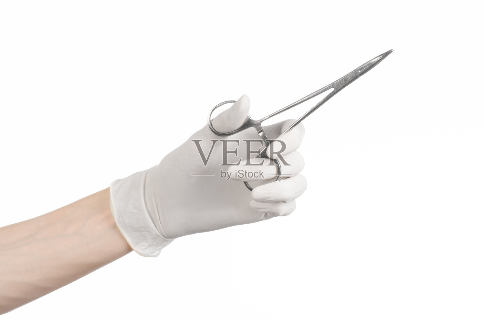 手术和医学主题:医生的手在白色的背景上拿着一个手术夹照片摄影图片