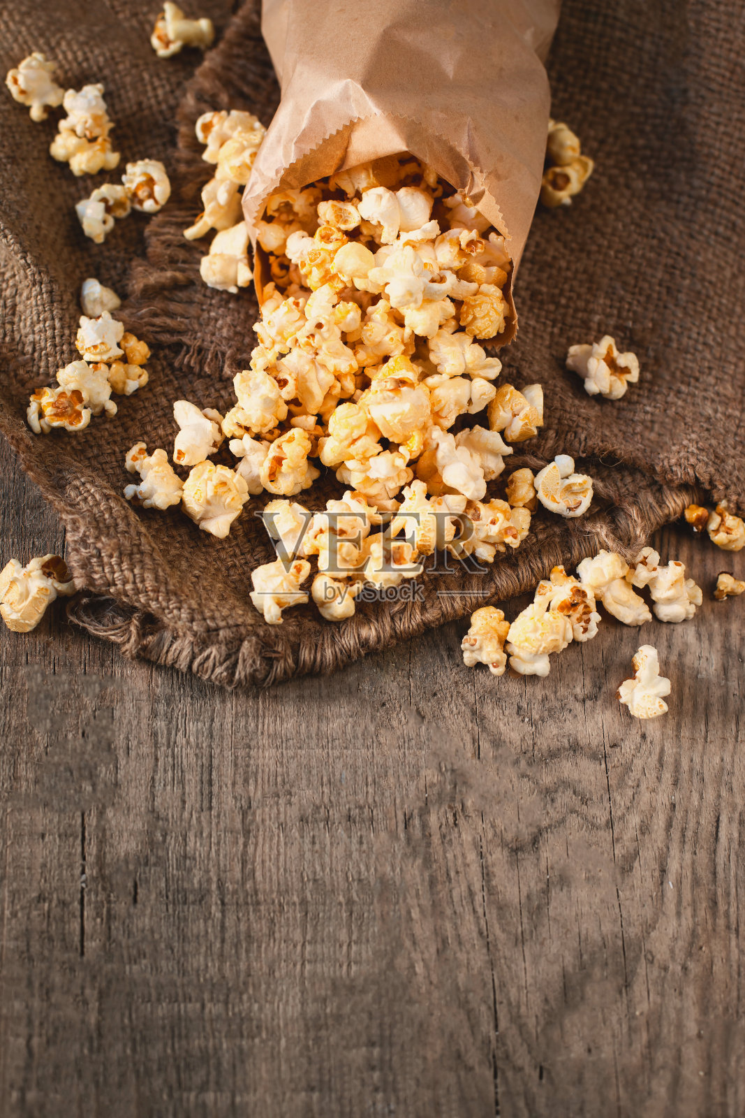 自制的爆米花，装在纸袋里。在木桌上放盐爆米花。电影的概念。快餐。前视图。本空间照片摄影图片