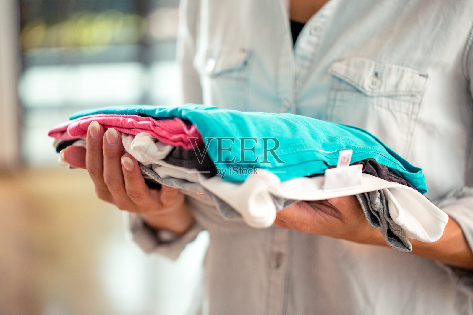 拿着叠好的衣服的女人照片摄影图片