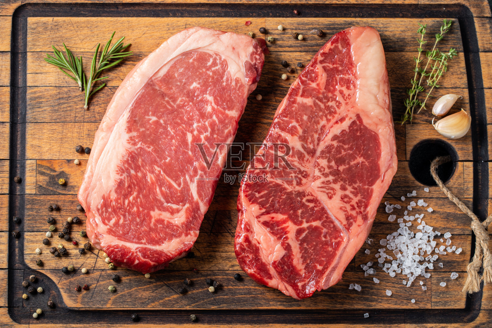 新鲜生的上等黑安格斯牛排配香料:Striploin, Rib Eye。前视图。在黑暗的背景下照片摄影图片