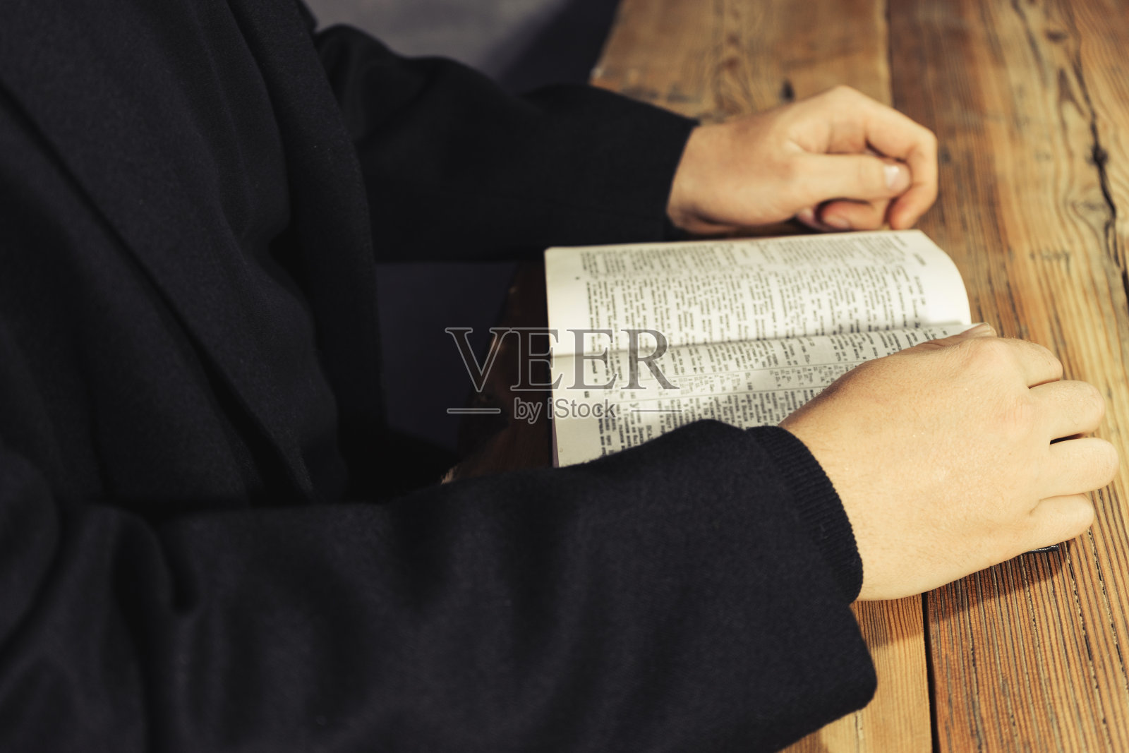 一个男人坐在一张古老的橡木桌子旁读圣经照片摄影图片