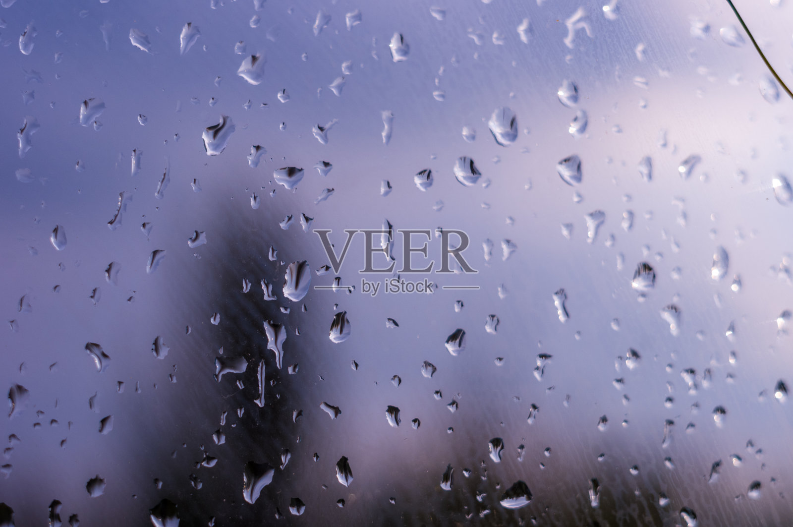 在多云的天空背景上，雨滴落在窗户玻璃上照片摄影图片