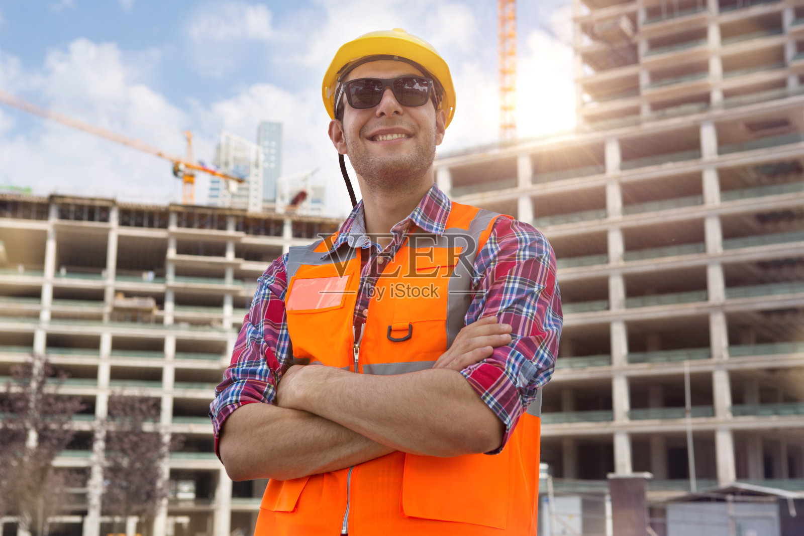 年轻工程师肖像与建筑工地和起重机背景。照片摄影图片