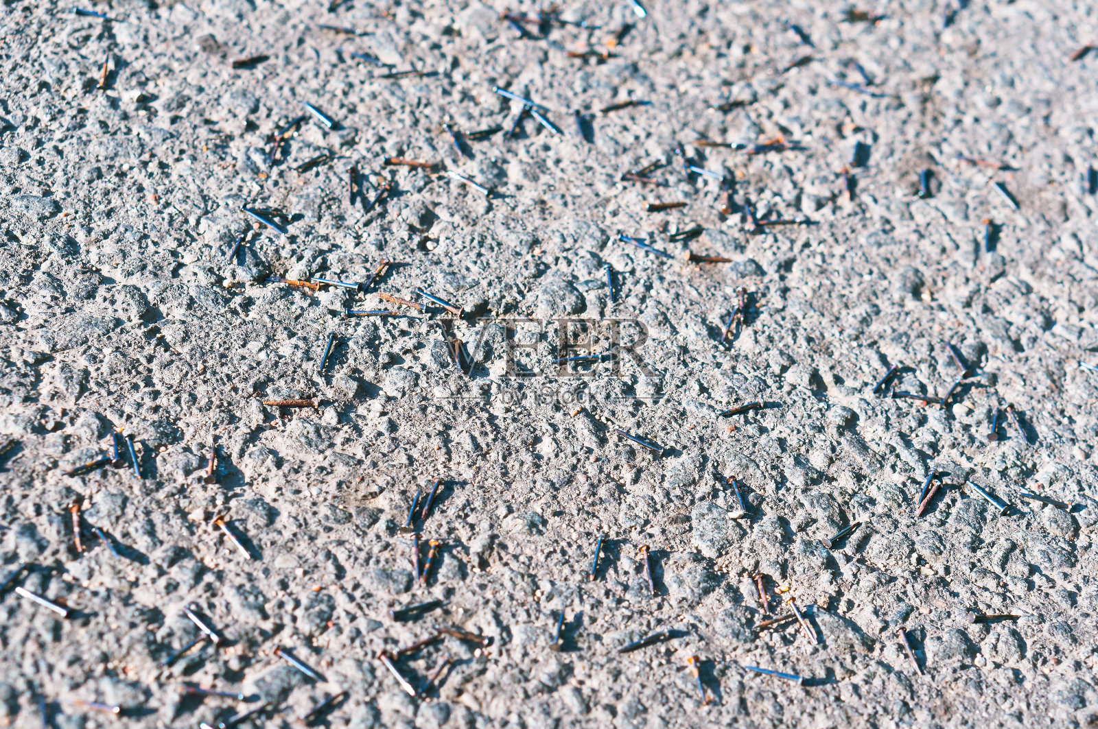 施工金属钉散落在路面上，小铁钉钉在路面上照片摄影图片