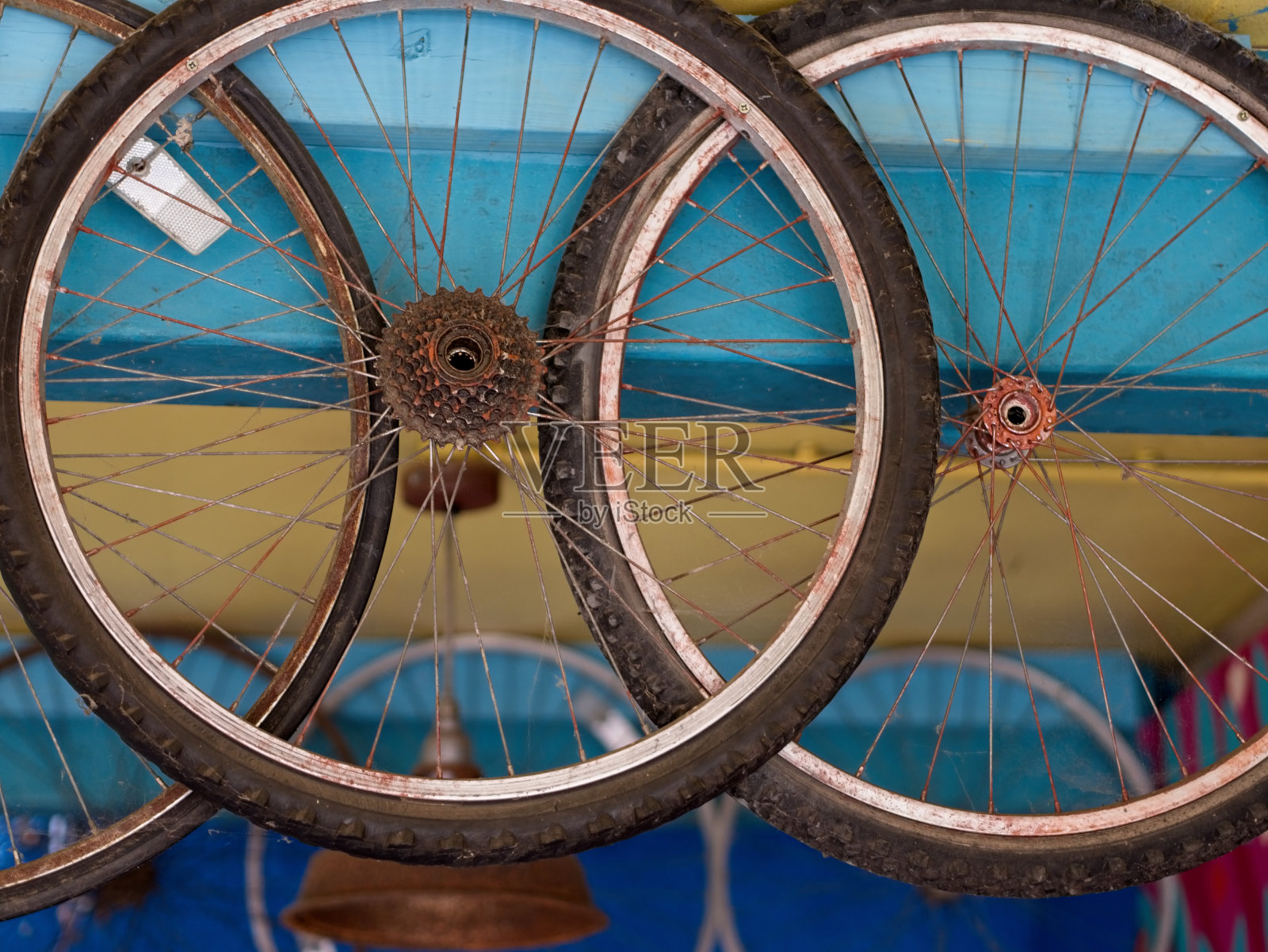 旧的尘土飞扬的乡村自行车修理厂。肮脏的轮子从五颜六色的天花板上垂下来。照片摄影图片