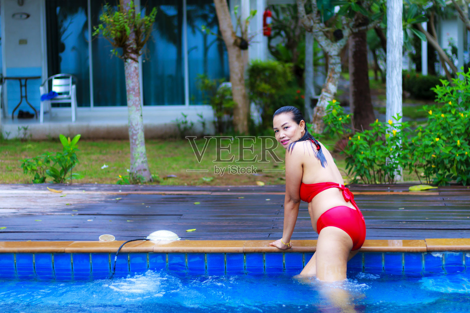 在游泳池里穿着红色比基尼的女人形状很漂亮照片摄影图片
