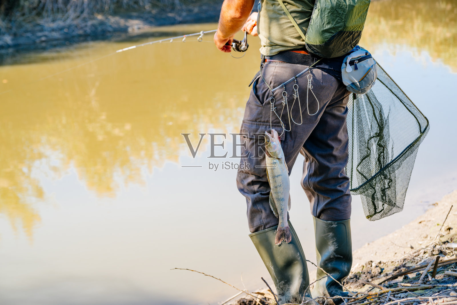 鱼用钓竿挂在渔夫的腰带上照片摄影图片