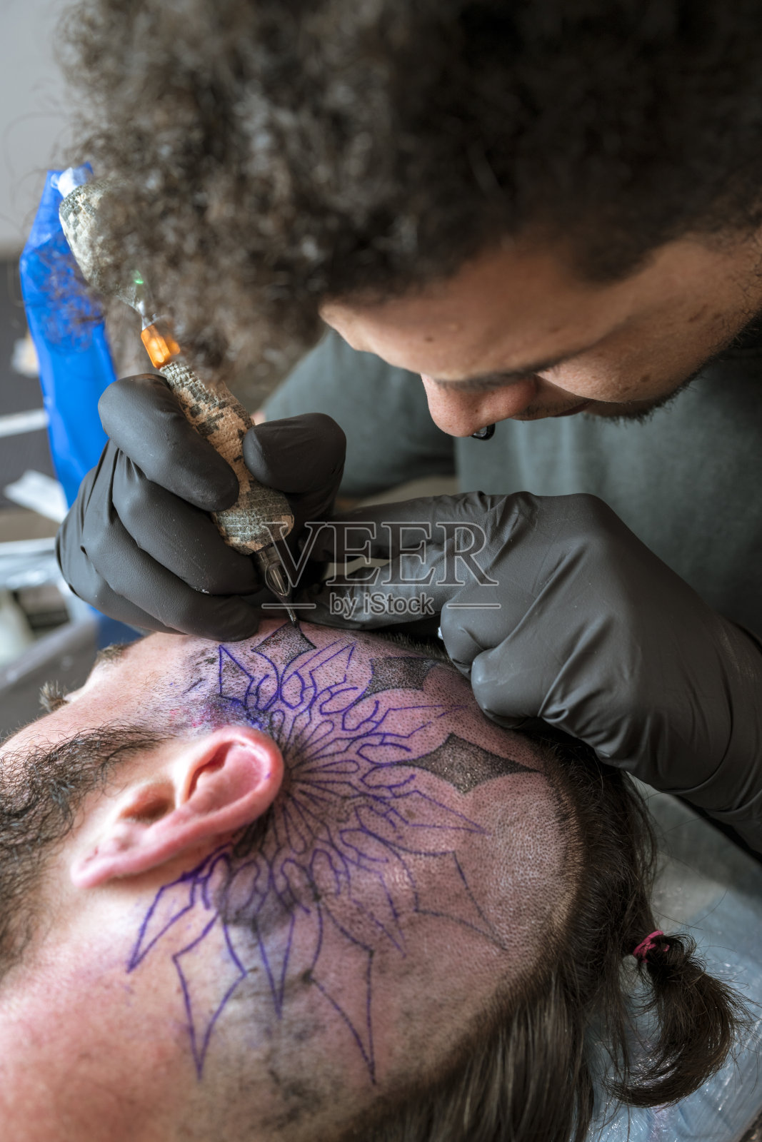 一个年轻人在一个男人的头上纹身照片摄影图片