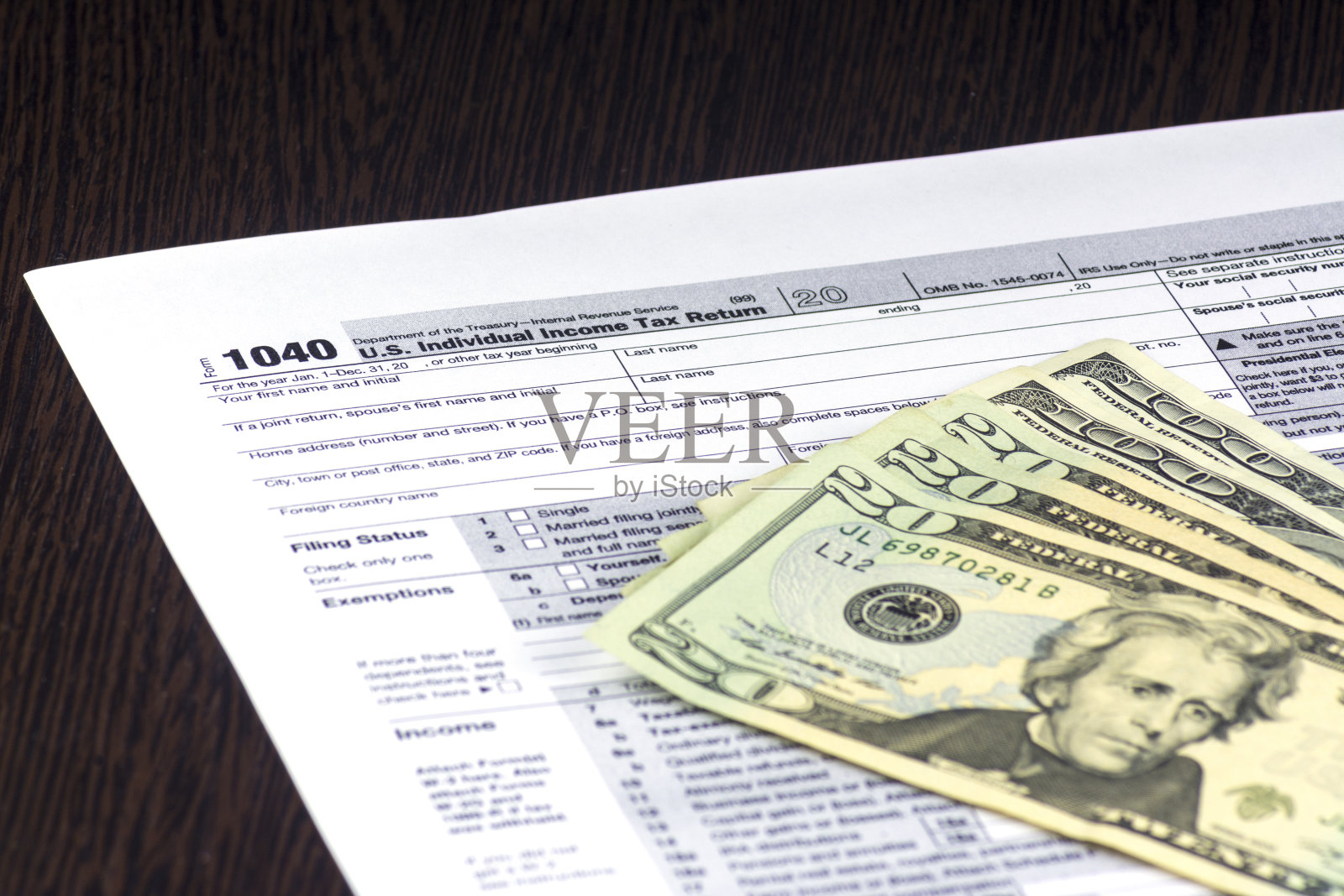 美国税单1040在桌子上。上面有几张钞票。20和100美元的现金照片摄影图片