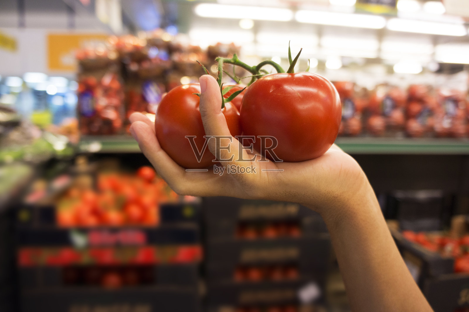 在市场上拿着和买着西红柿的女人。照片摄影图片