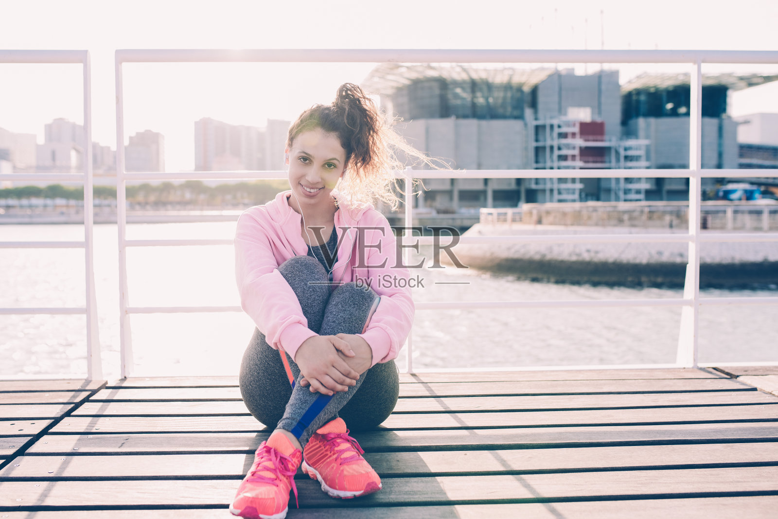 戴着耳机的微笑健康女孩正在码头休息照片摄影图片