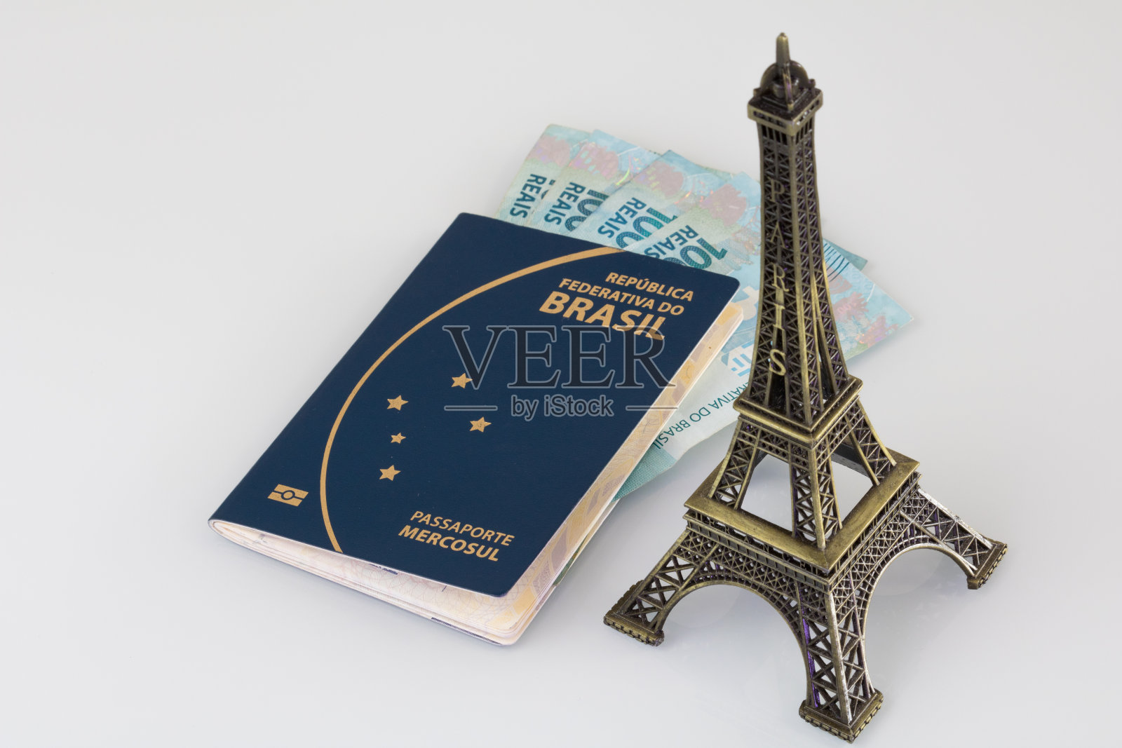 巴西护照(翻译为“巴西共和国联邦共同市场护照”)，百元钞票和埃菲尔铁塔的白色背景。照片摄影图片