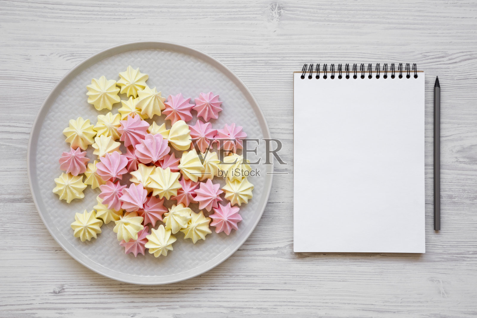 灰色的盘子和空白的记事本，白色的木质背景，俯视视图。平躺，从上面俯视。照片摄影图片