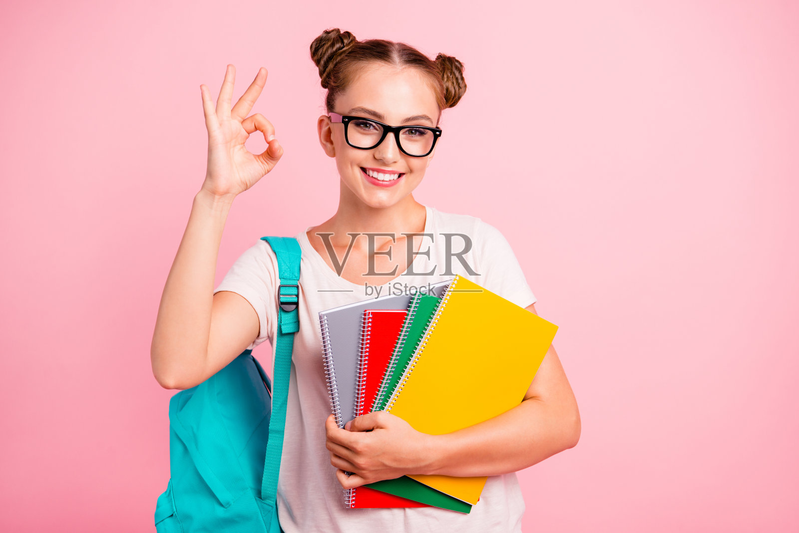 家庭作业很容易!甜美可爱的读者女孩显示ok标志手拿彩色笔记本孤立在亮粉色的背景照片摄影图片