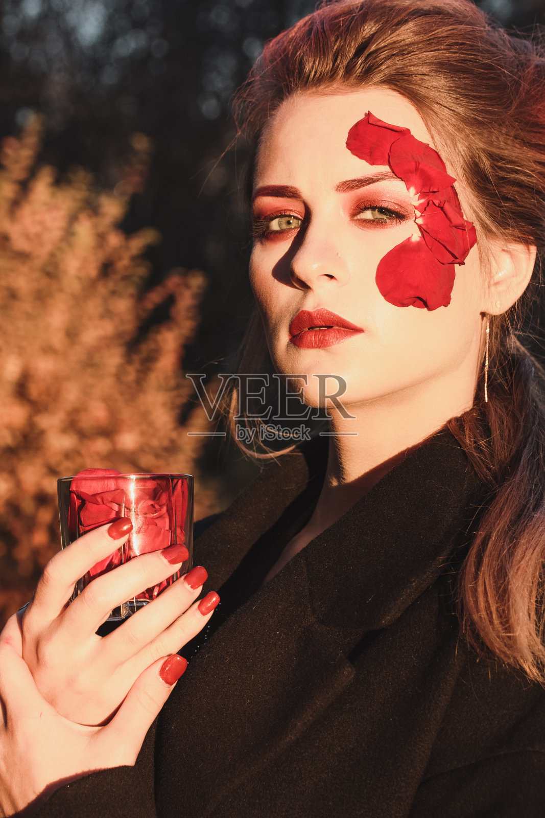 美丽的少女与贴花红玫瑰花在脸上的自然秋天照片摄影图片