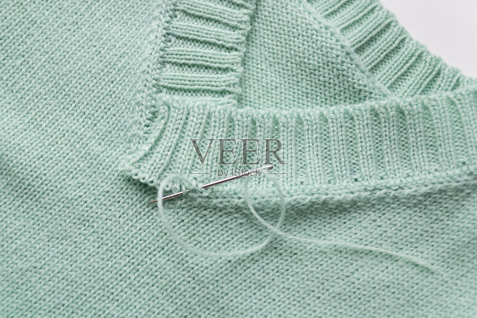 一个由绿色羊毛制成的v领的特写。针织没有完成照片摄影图片