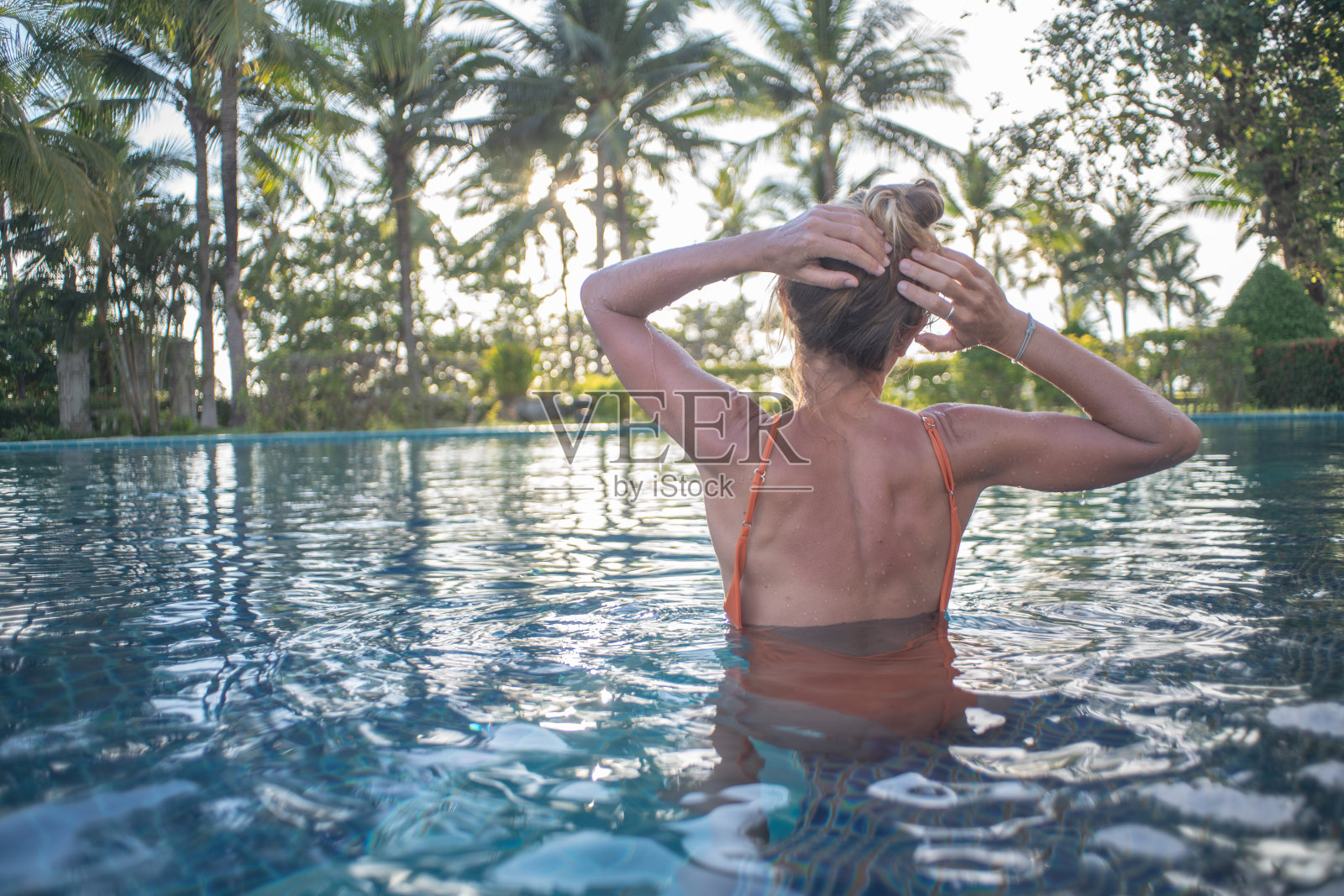 女孩享受度假水疗健康在热带天堂-女人放松池户外在豪华度假水疗撤退。快乐的年轻女模特放松休息在水上度假旅游。照片摄影图片
