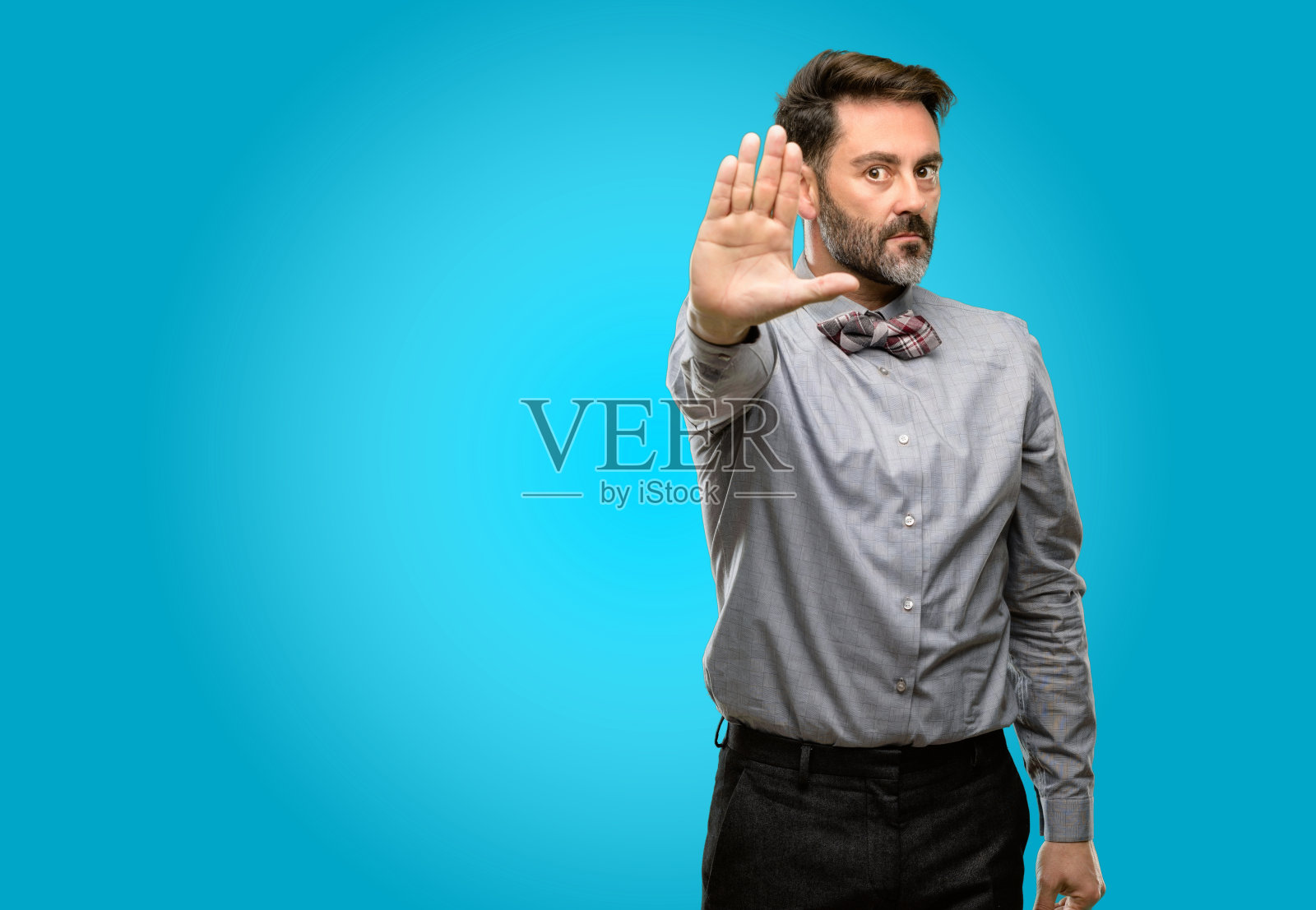 中年男子，留着胡子，打着领结，对恶劣的态度很生气，用手做停止手势，说不，表示安全，防御或限制，可能会推照片摄影图片