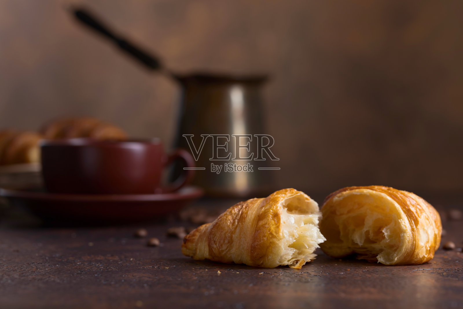 新鲜美味的羊角面包和一杯咖啡在旧铜背景。照片摄影图片