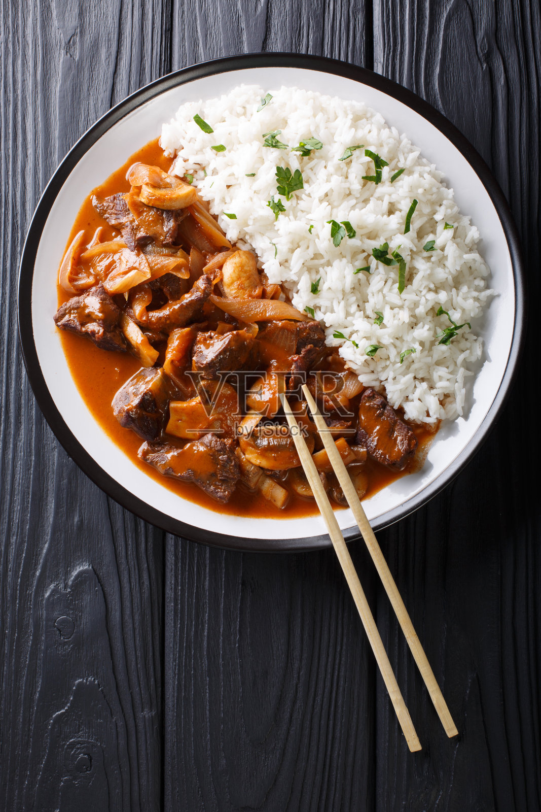 日本料理:辛辣的牛肉加洋葱和蘑菇，以及米饭(林饭)特写。垂直的俯视图照片摄影图片
