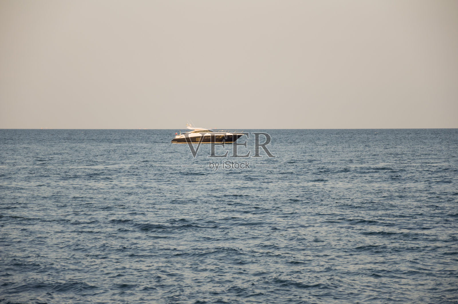 黑海。17、水无波，小船远。前面有块大石头。保持冷静。主要是多云的天气。蓝色和灰色。在下雨之前照片摄影图片