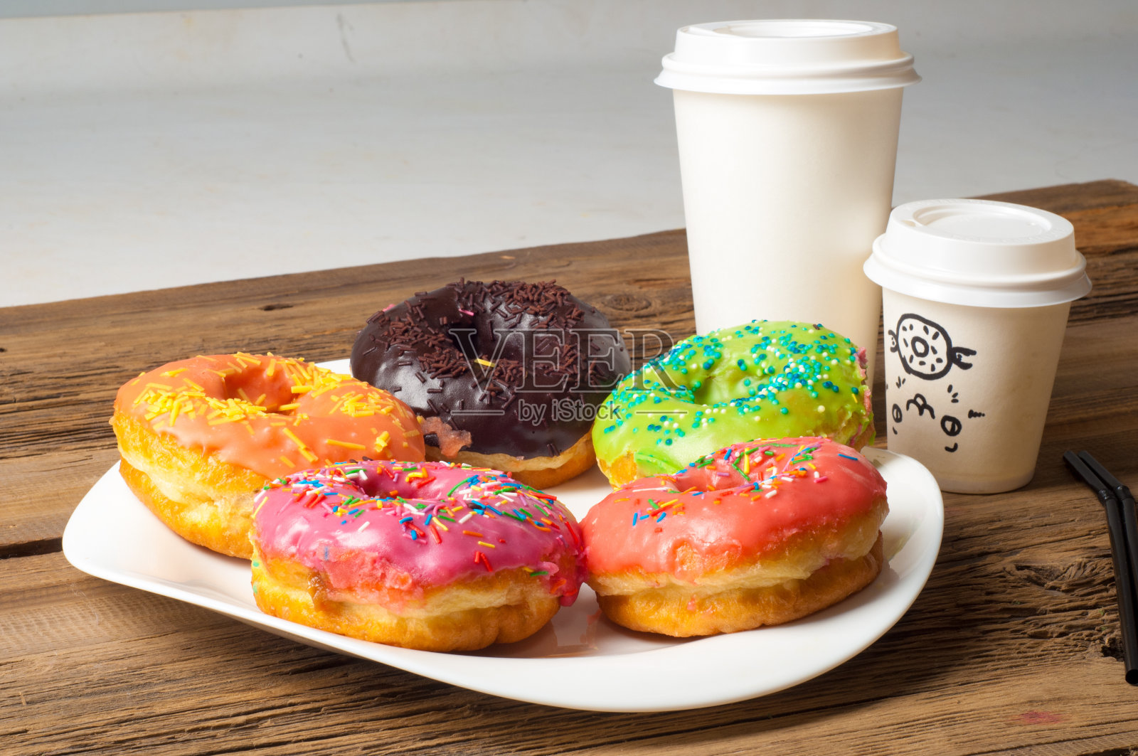 彩色釉面甜甜圈。在一个白色的盘子上，在木板上。咖啡甜甜圈照片摄影图片