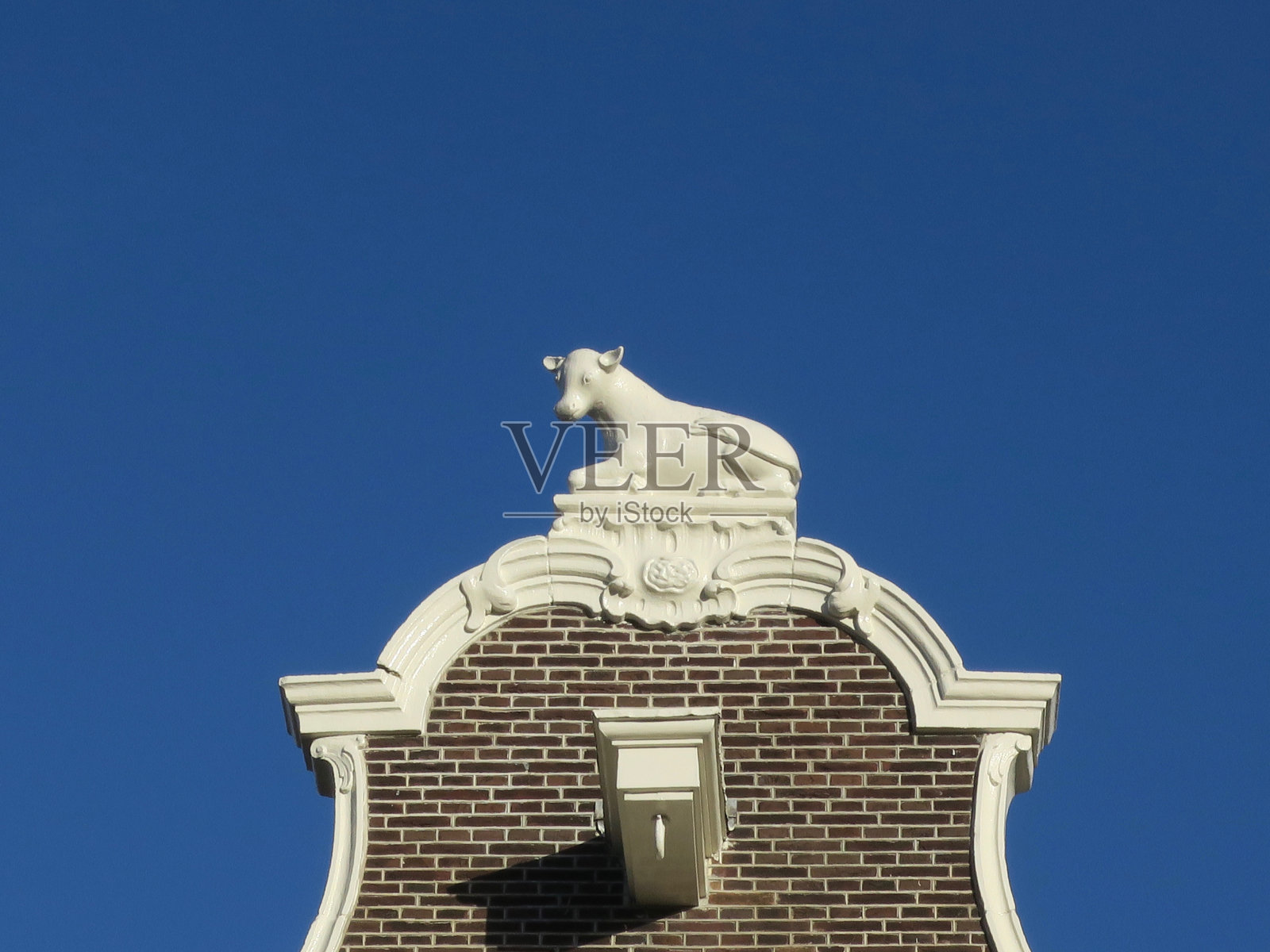 阿姆斯特丹一处运河房屋正面顶部的白奶牛雕像照片摄影图片