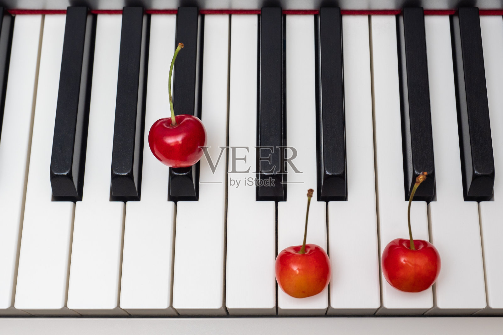 钢琴和弦A#/Bb大调，琴键上的樱桃照片摄影图片