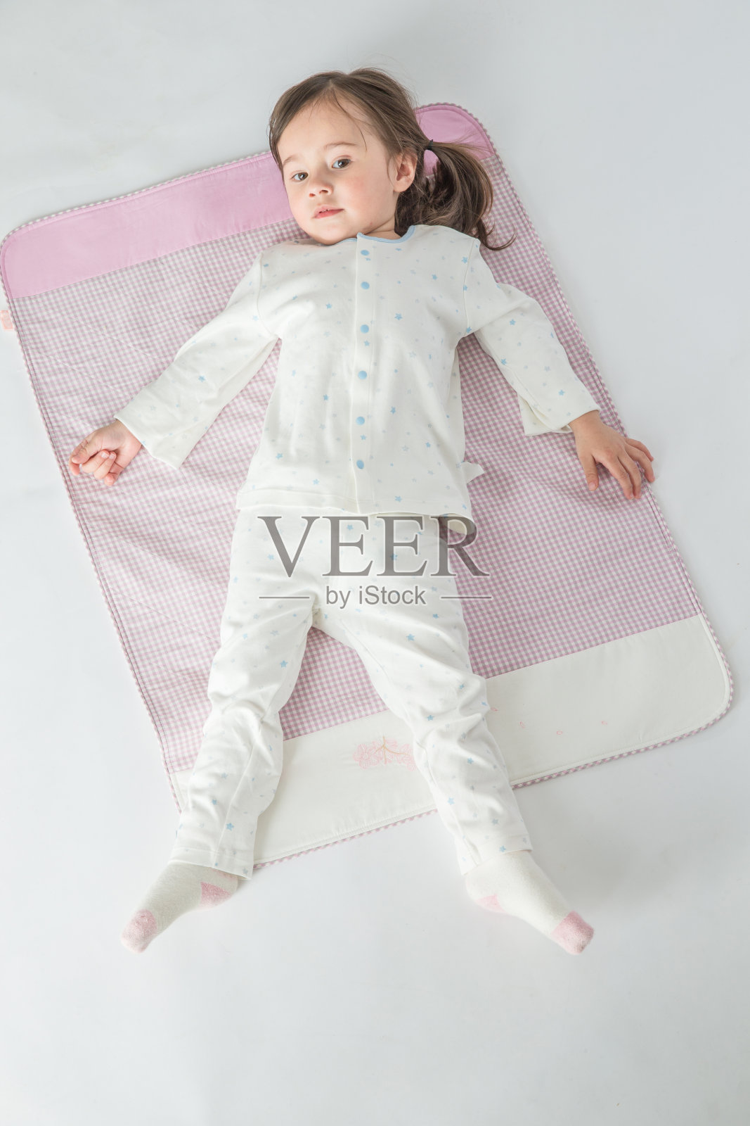 那个快乐的小女孩正躺在粉红色的垫子上照片摄影图片